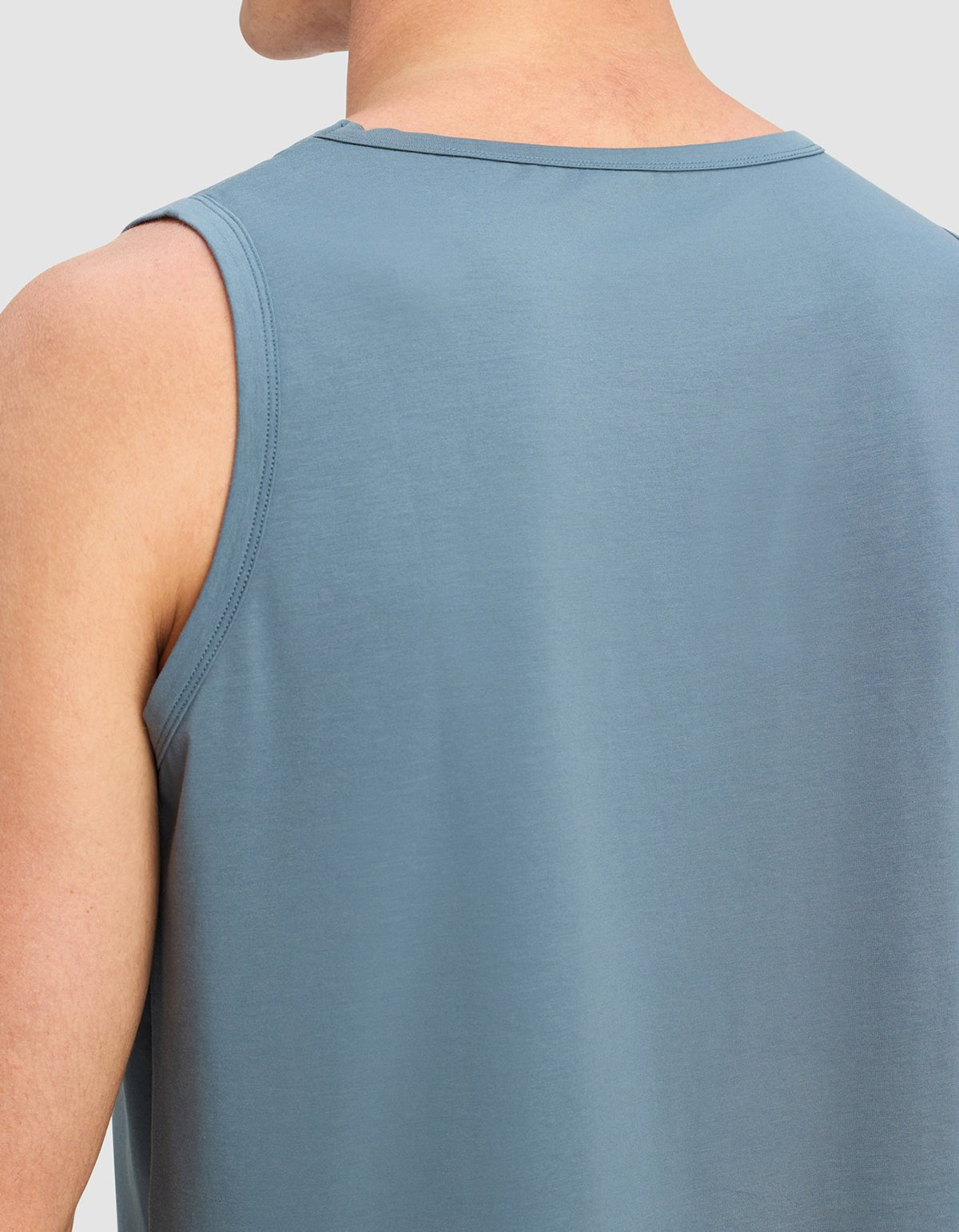 A close-up of a man's upper back and shoulder wearing the Cozy Earth Men's First Layer Pajama Tank in light blue, shown from behind against a plain background.|Color:Dawn
