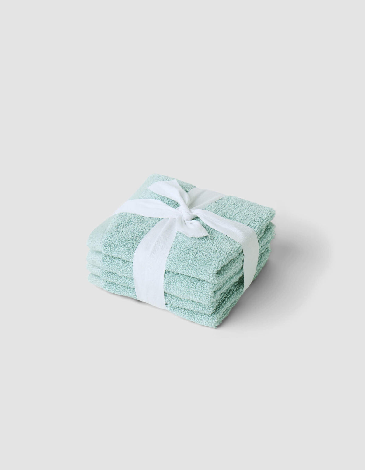 A neatly folded stack of Cozy Earth Complete Cleansing Cloths, tied with a white ribbon and placed on a plain light gray background.|Color:Tide