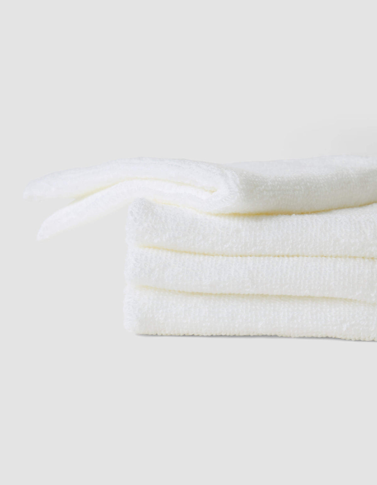 A stack of three neatly folded white Cozy Earth Complete Cleansing Cloths is displayed against a plain light gray background.|Color:White