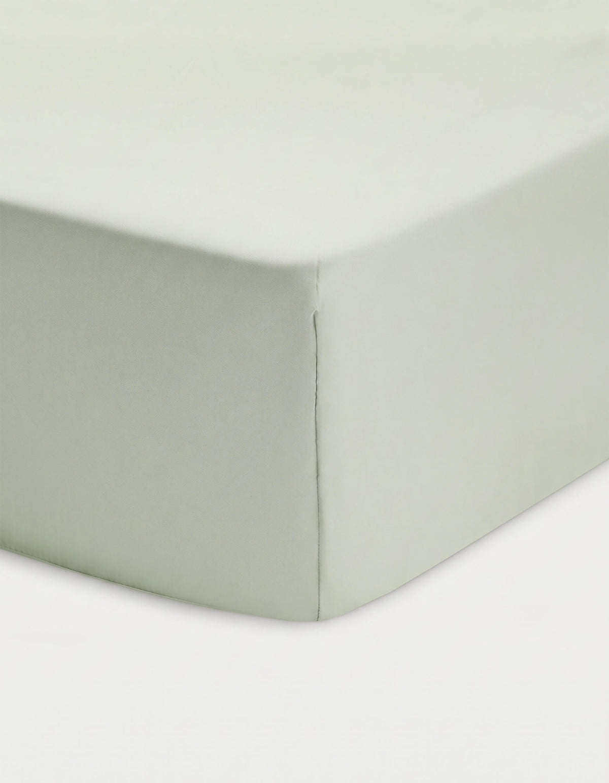 Close-up of a corner of a bed showcasing the Cozy Earth Bamboo Fitted Sheet in light green, neatly covering the mattress against a white background.|Color:Laurel