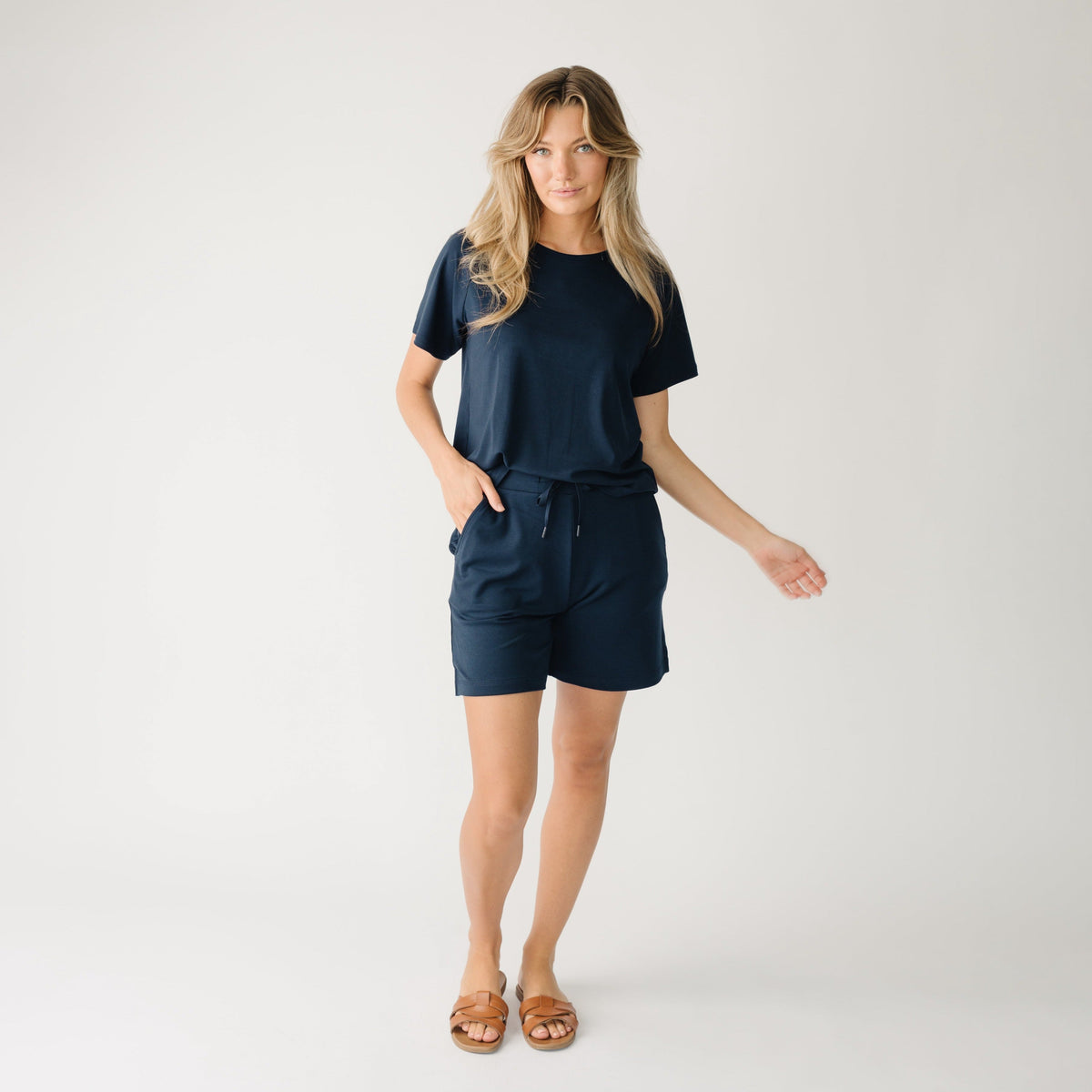 Woman wearing a navy t-shirt and navy Cozy Earth Brushed Bamboo Mid-Length Shorts shorts on a plain background |Color:Navy