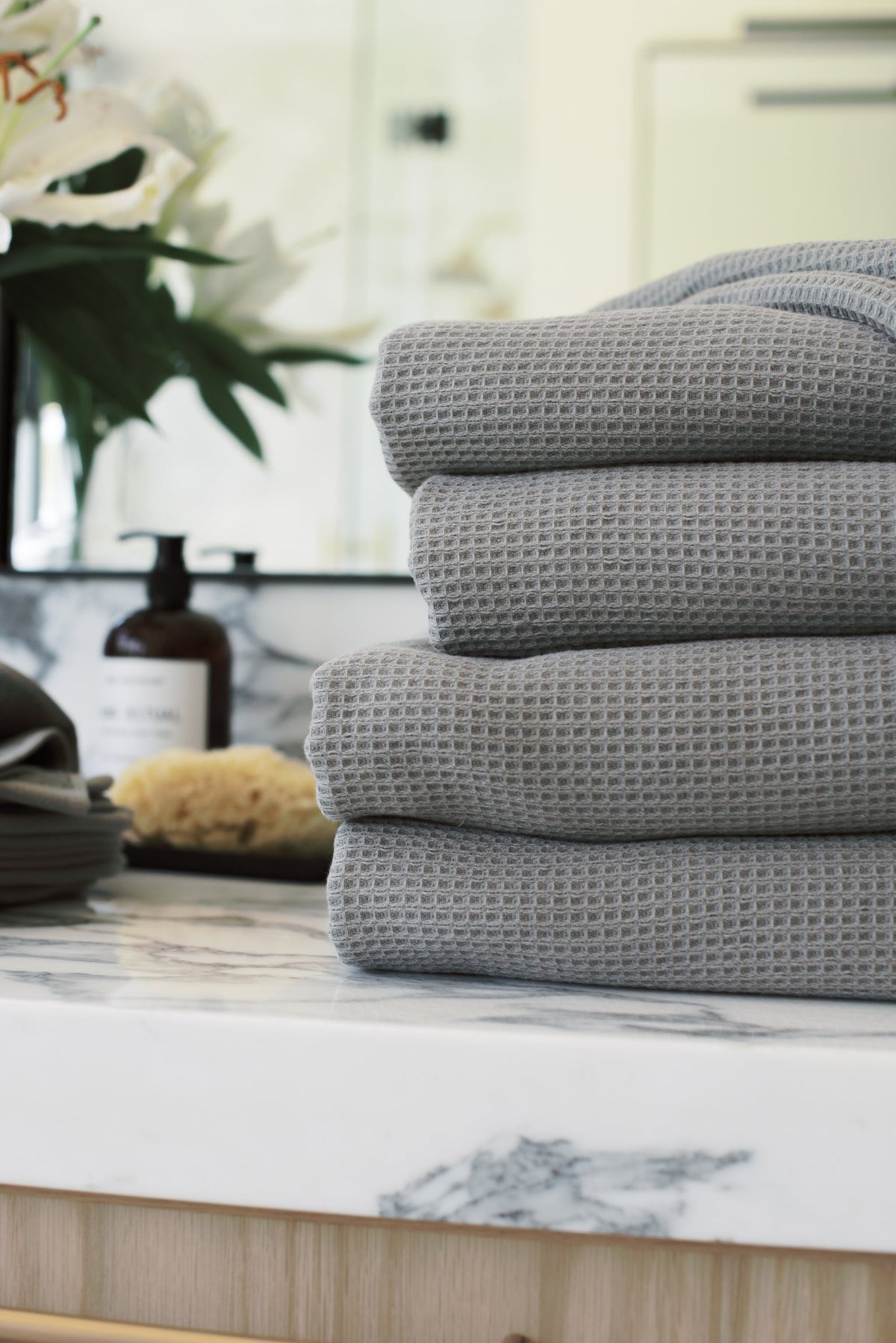Waffle Bath Towel in the color Charcoal. Photo of Charcoal Waffle Bath Towel taken with Charcoal Waffle Bath Towel resting on a bathroom sink. |Color:Charcoal
