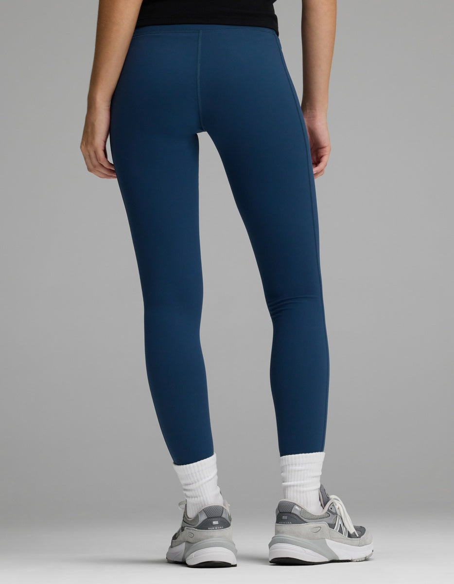Rear view of a person wearing solid blue Women’s Liv Leggings, white crew socks, and grey athletic sneakers.|Color:Obsidian