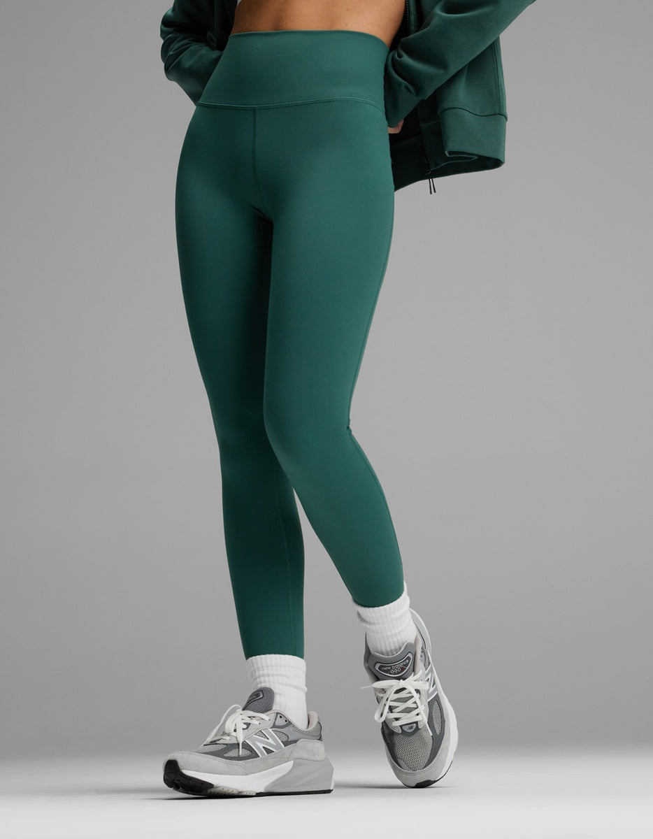 A person wearing dark green Cozy Earth Women’s Liv Leggings, white socks, and grey athletic sneakers.|Color:Uniform