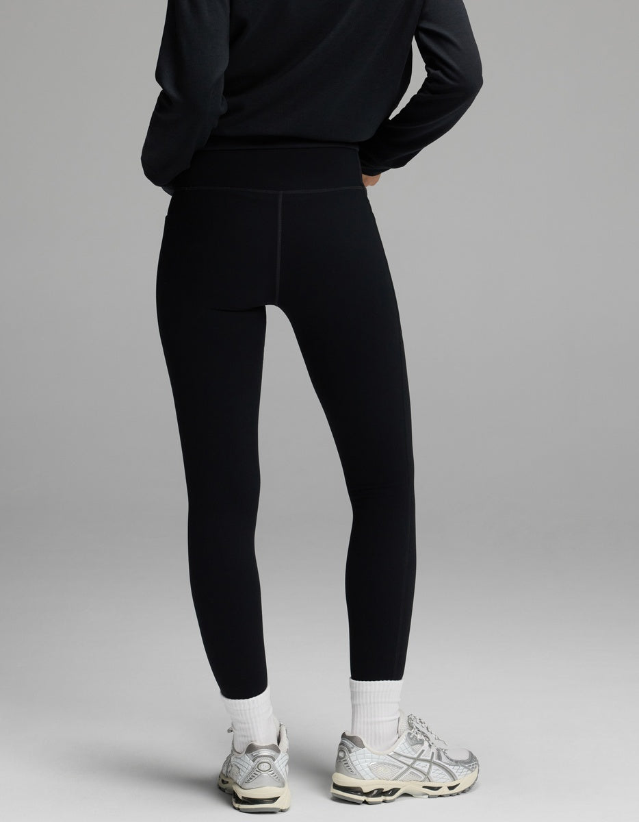 A person wearing black Women’s Liv Leggings with Pockets, white socks, and athletic shoes, viewed from behind.|Color:Jet Black