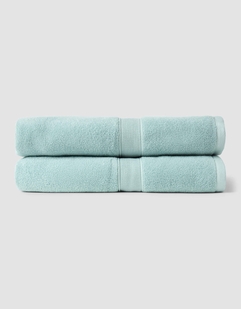 Two neatly folded light blue towels from the Cozy Earth Complete Luxe Bath Bundle are stacked against a plain, light gray background.|Color:Tide