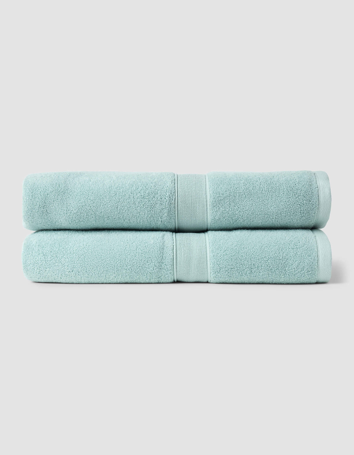 Two neatly folded light blue towels from the Cozy Earth Complete Luxe Bath Bundle are stacked against a plain, light gray background.|Color:Tide