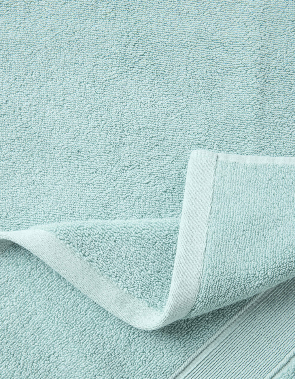 A close-up of the Luxe Bath Sheets by Cozy Earth in light blue highlights their textured, soft surface and neatly folded edge, showcasing the towel’s plush thickness and detailed hem.|Color:Tide