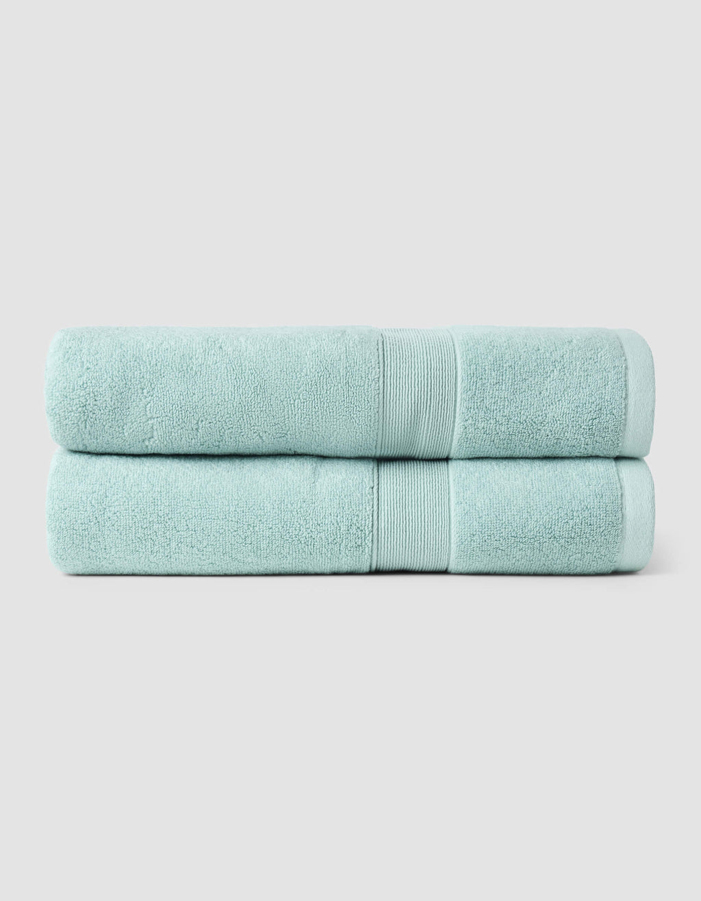 Two Luxe Bath Towels from Cozy Earth, neatly folded and stacked, displayed against a plain light gray background.|Color:Tide
