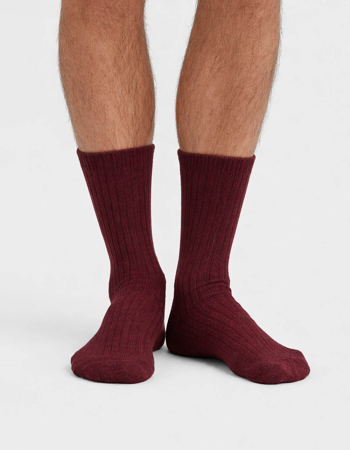 A close-up of a person's lower legs and feet wearing Cozy Earth’s The Plush Lounge Calf Sock 3-Pack in burgundy, ribbed, quarter-length style, set against a plain white background.|Color:Burgundy/Rouge/Dusty Rose