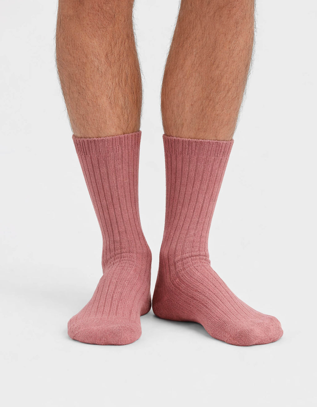 A close-up of a person's lower legs and feet wearing Cozy Earth’s The Plush Lounge Calf Sock 3-Pack in pink, ribbed, calf-length style, set against a plain white background.|Color:Burgundy/Rouge/Dusty Rose