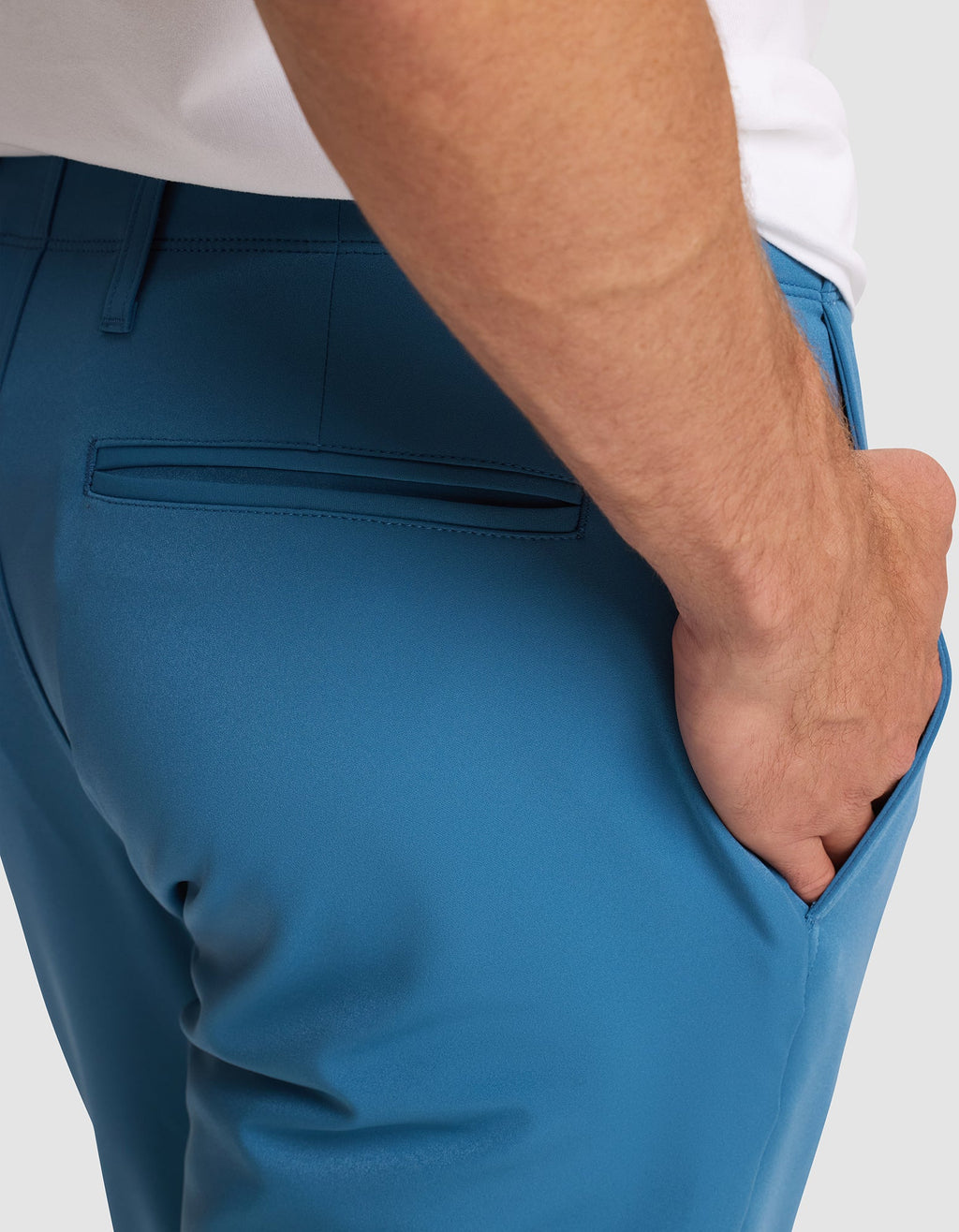 A man wearing Cozy Earth’s Men's Everywhere Pant in bright blue, shown from the waist down with his right hand in his pocket. The pants feature a back welt pocket and a white shirt is partially visible.   |Color:Wave