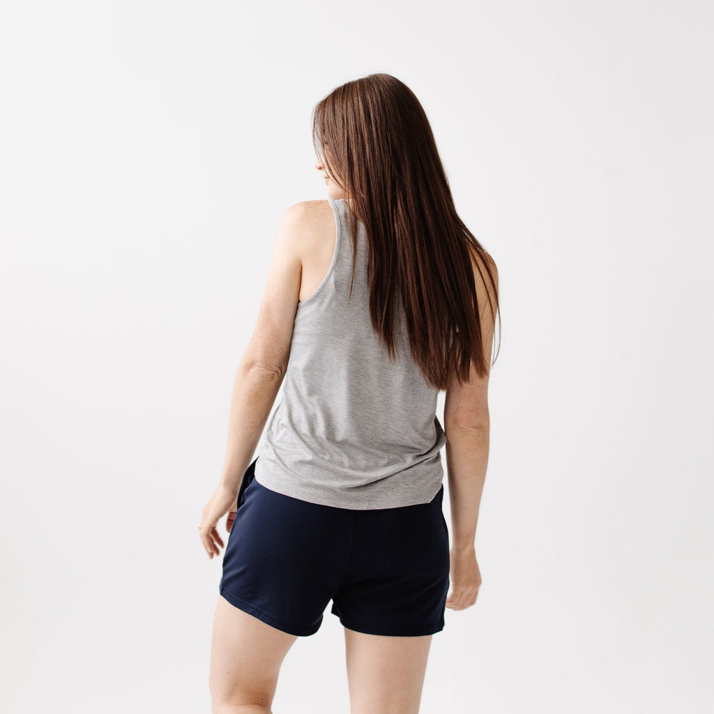 A woman facing backwards wearing Cozy Earth Brushed Bamboo Jogger Shorts in navy and a gray top on a light background |Color:Navy