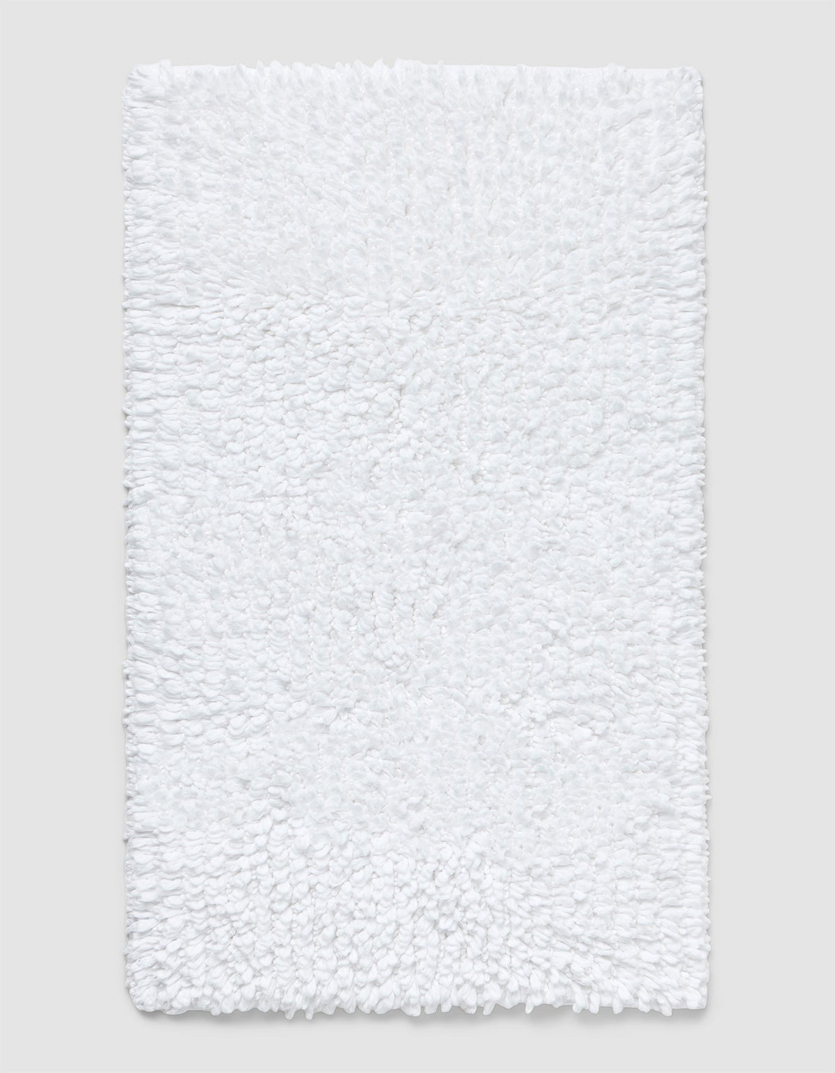 The Cozy Earth Plush Loop Bath Mat is rectangular, white, and features a soft, fluffy chenille shag texture. Shown on a plain light background, it offers plush comfort with its textured surface.|Color:White