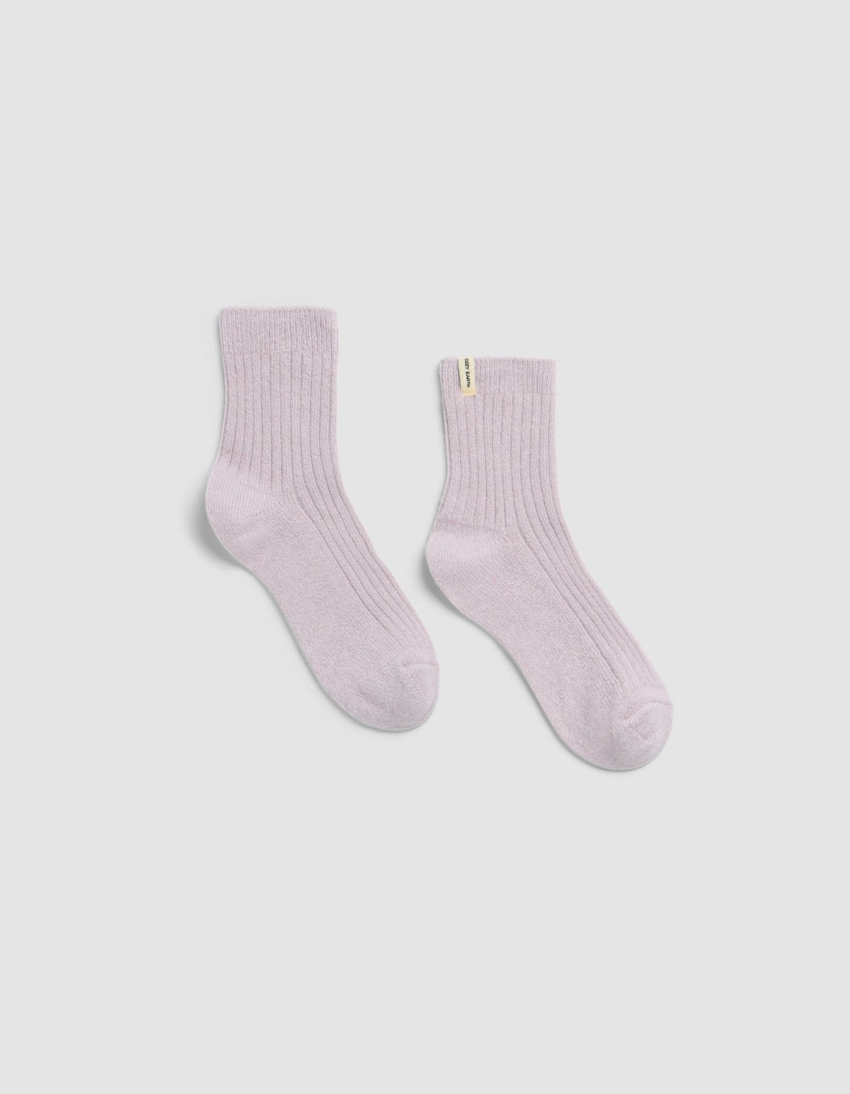 The Plush Lounge Quarter Socks by Cozy Earth in light pink features a ribbed design and a small yellow tag on one sock, shown against a plain white background.|Color:Lavender