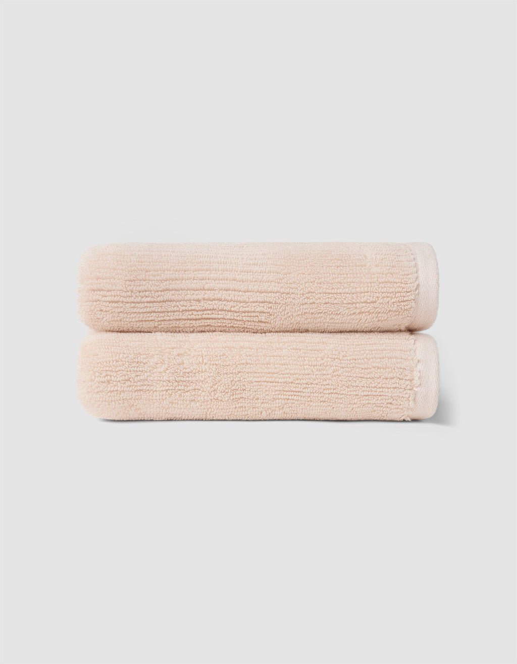 The Cozy Earth Complete Ribbed Terry Bath Bundle features two neatly folded, light beige towels stacked atop each other against a plain, light gray background.|Color:Petal
