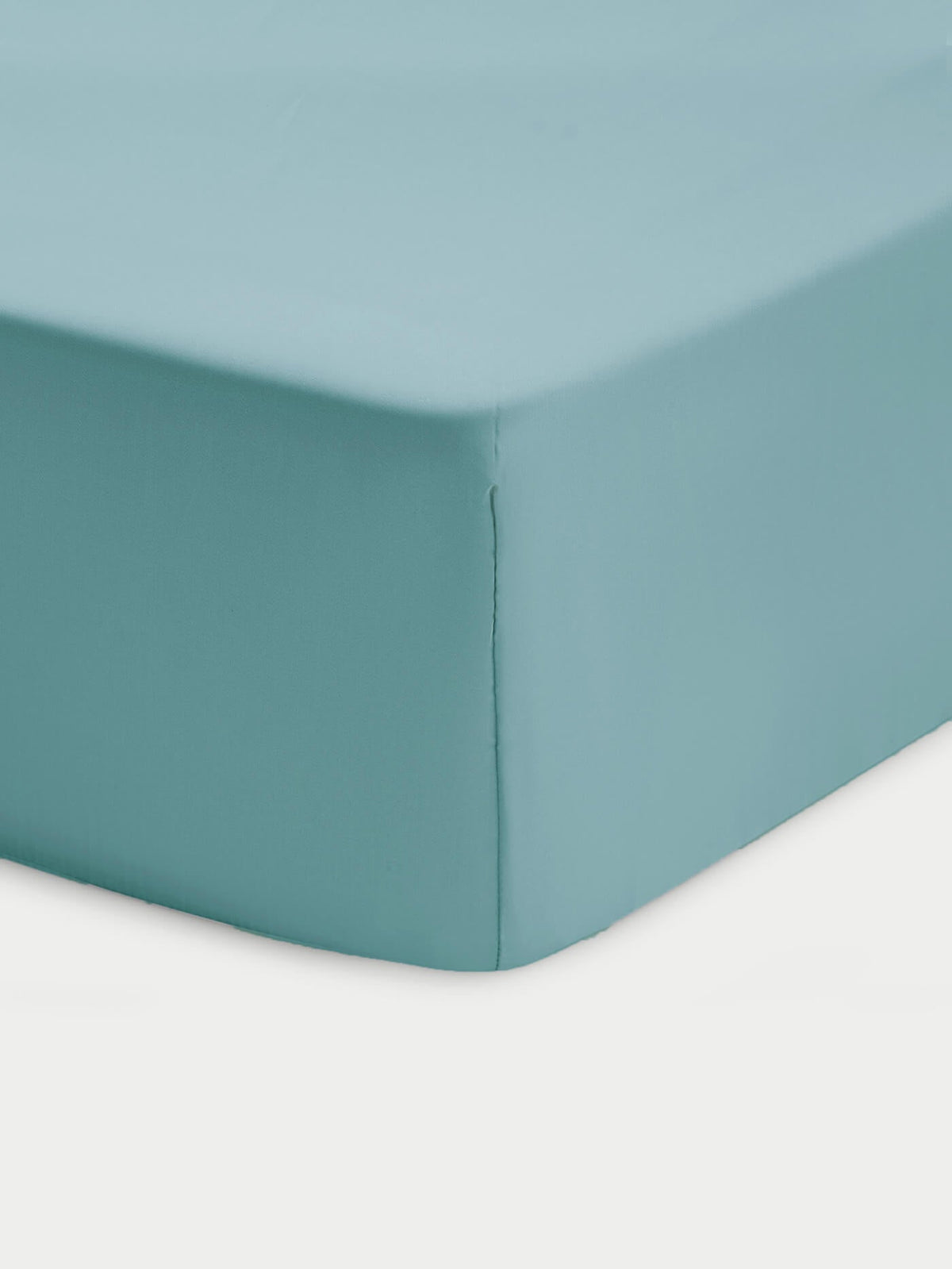 Close-up of a corner of a bed showcasing the Cozy Earth Bamboo Fitted Sheet in light blue, neatly covering the mattress against a white background.|Color:River
