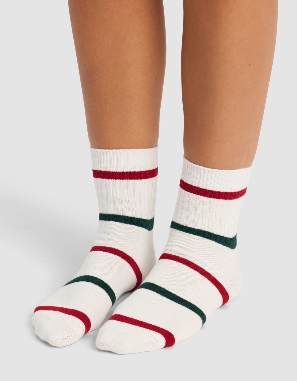 A pair of feet wearing Cozy Earth's Women's Sadie Sock—white crew socks with red and dark green stripes—stand on a light background.|Color:Jade/Crimson