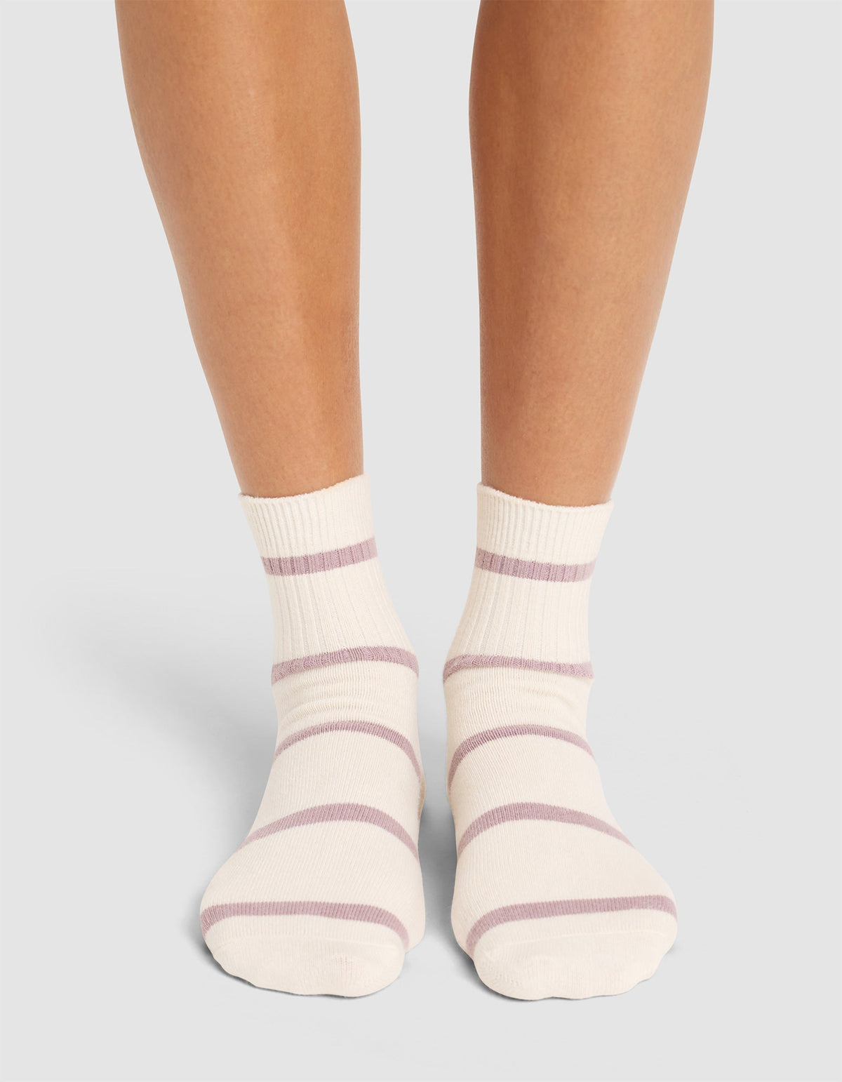 A person stands with feet close together on a light surface, wearing Cozy Earth Women's Sadie Socks—cream-colored with light purple horizontal stripes. |Color:Parchment/Dusty Orchid