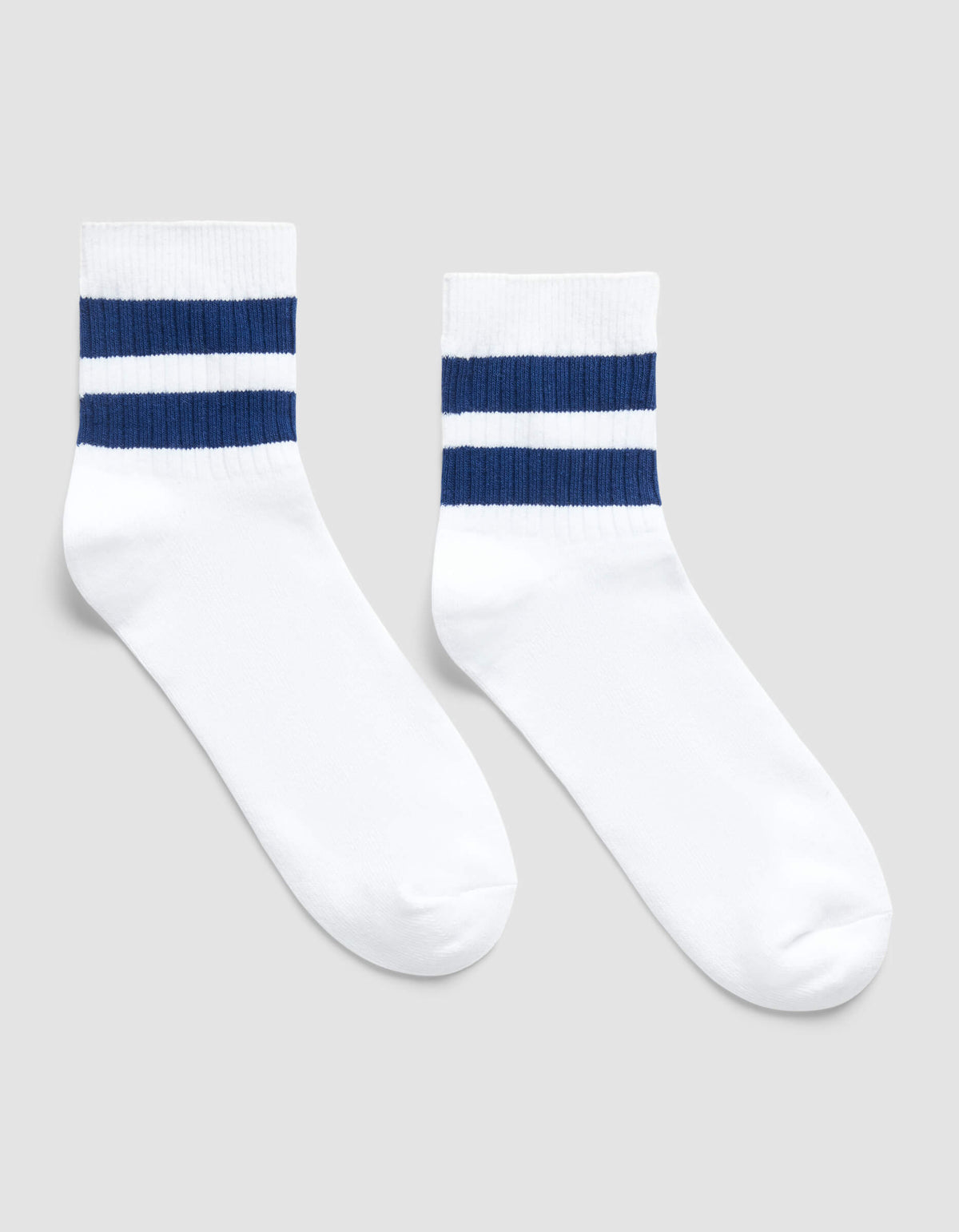 The Women's Sadie Sock by Cozy Earth is a white crew sock featuring two horizontal navy blue stripes near the top, shown on a light gray background.|Color:White/Pacific