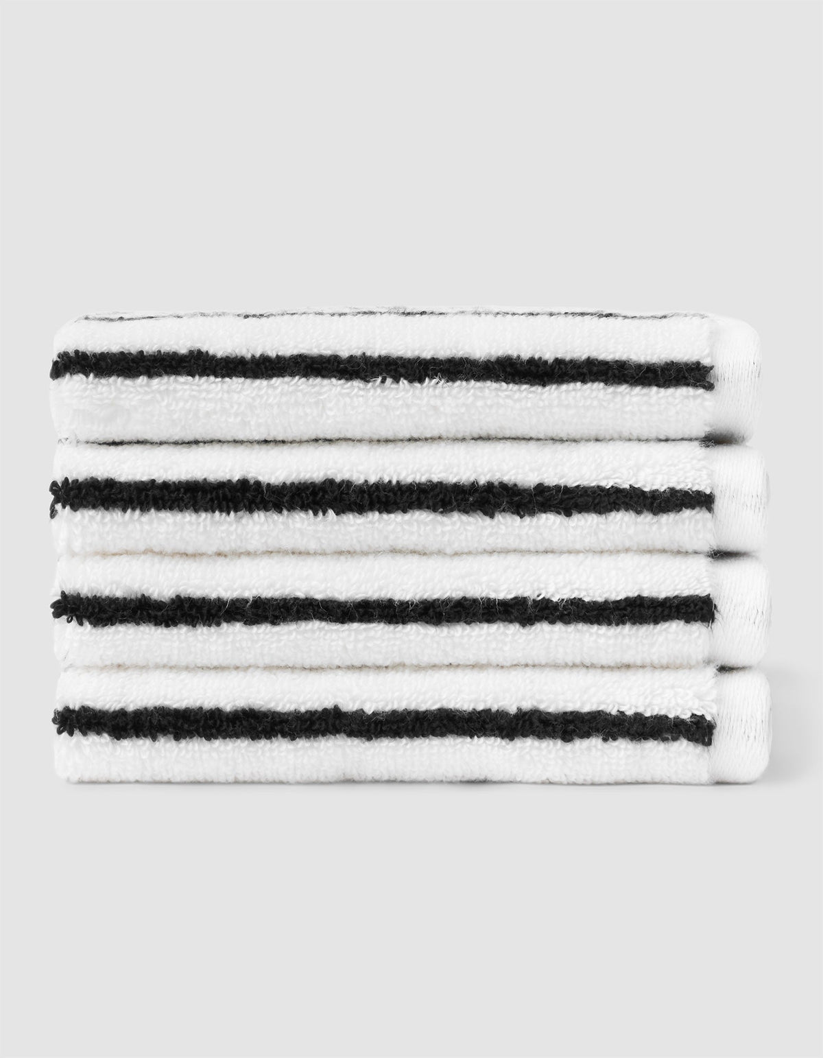 A stack of four neatly folded Cozy Earth Striped Luxe Washcloths in white with evenly spaced black stripes, set against a plain light gray background. |Color:Black Stripe
