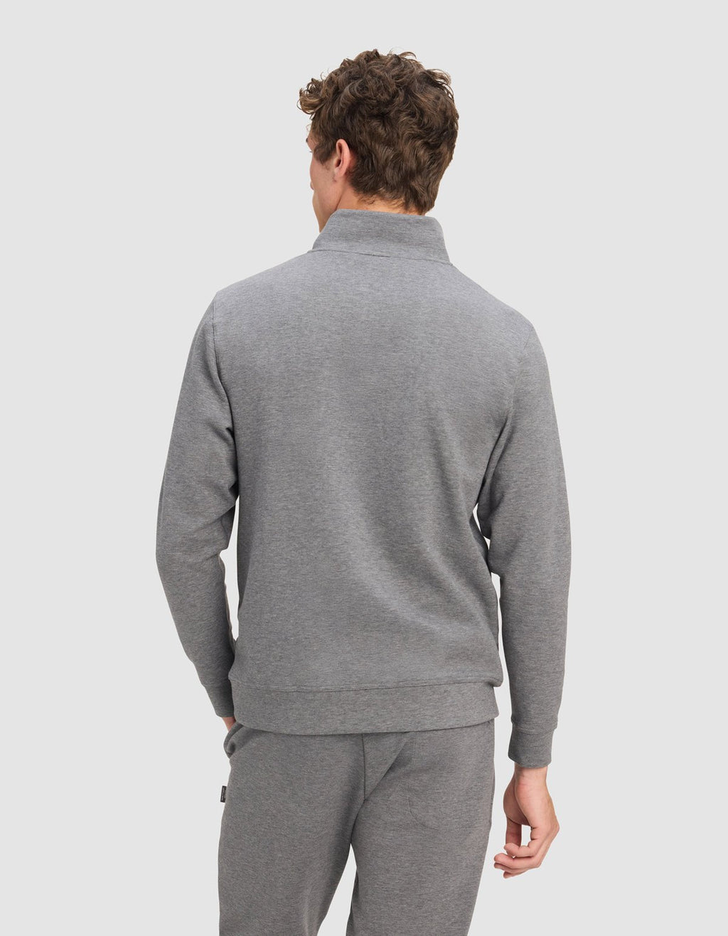 A man with curly brown hair, shown from the back against a light gray background, wears the Cozy Earth Men's StretchTech Quarter Zip in light gray.|Color:Coal Heather