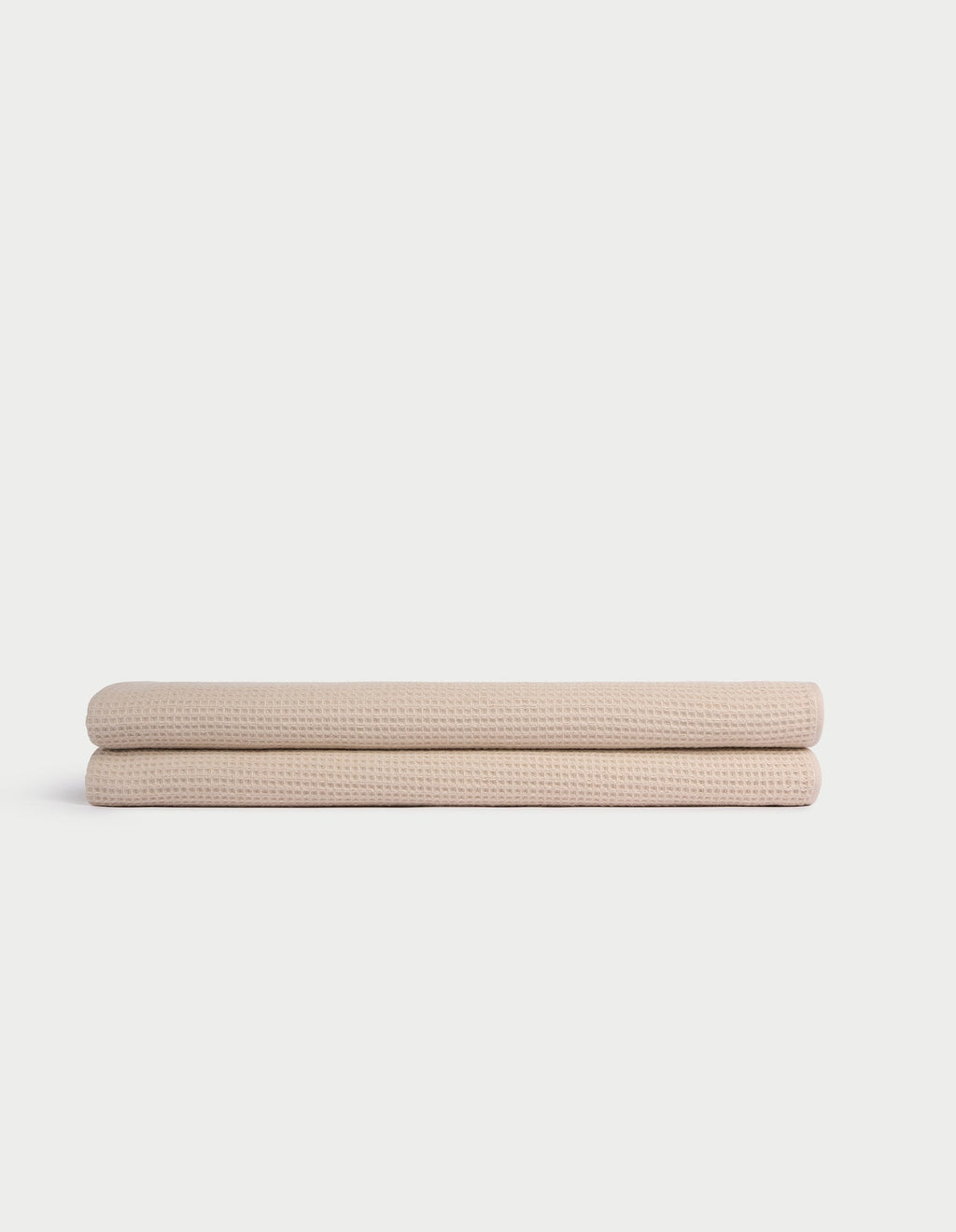 Two Cozy Earth Waffle Bath Sheets, beige and neatly folded, are stacked atop one another against a plain white background. |Color:Birch