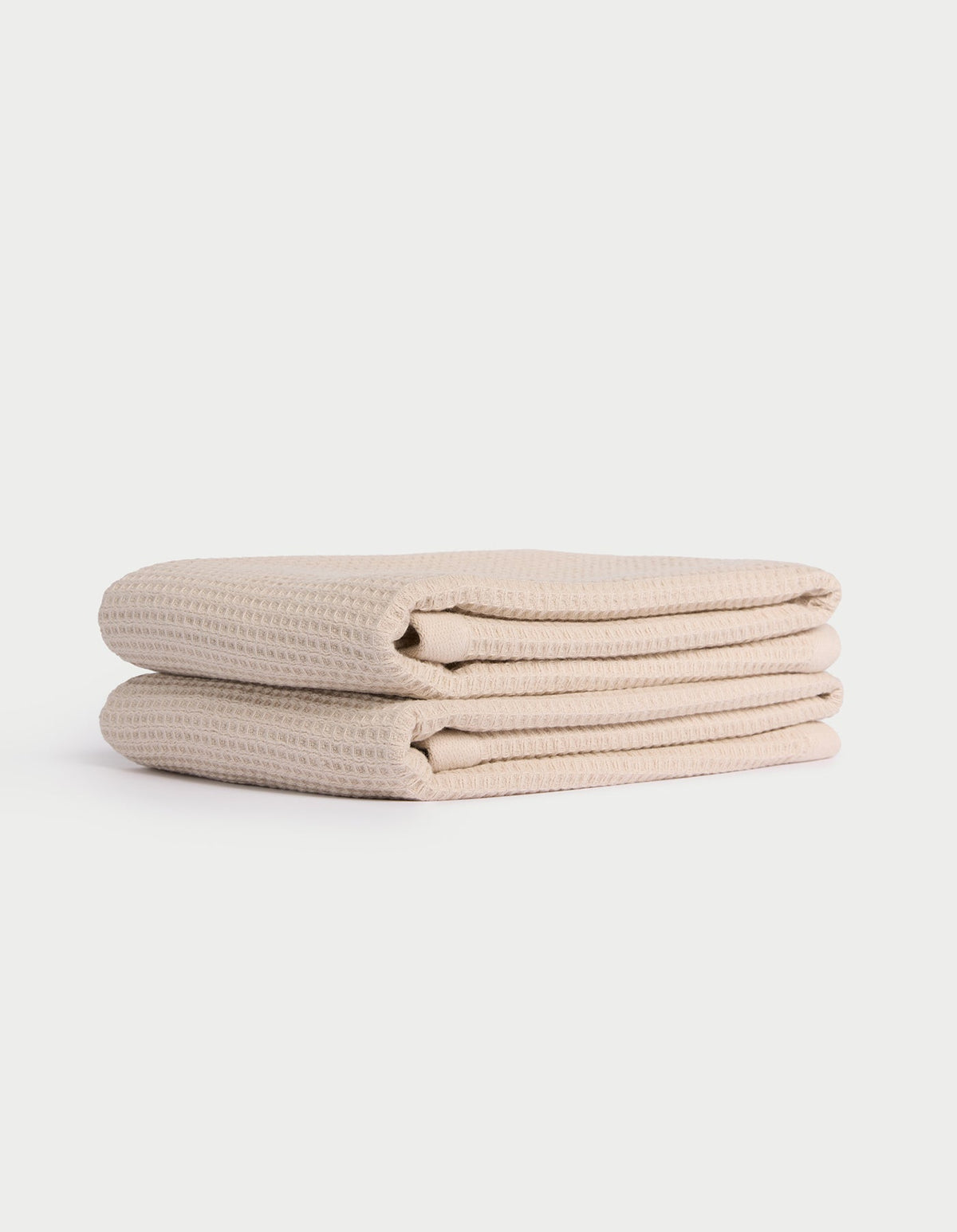 Two neatly folded beige Cozy Earth Waffle Hand Towels stacked atop each other against a plain white background. |Color:Birch