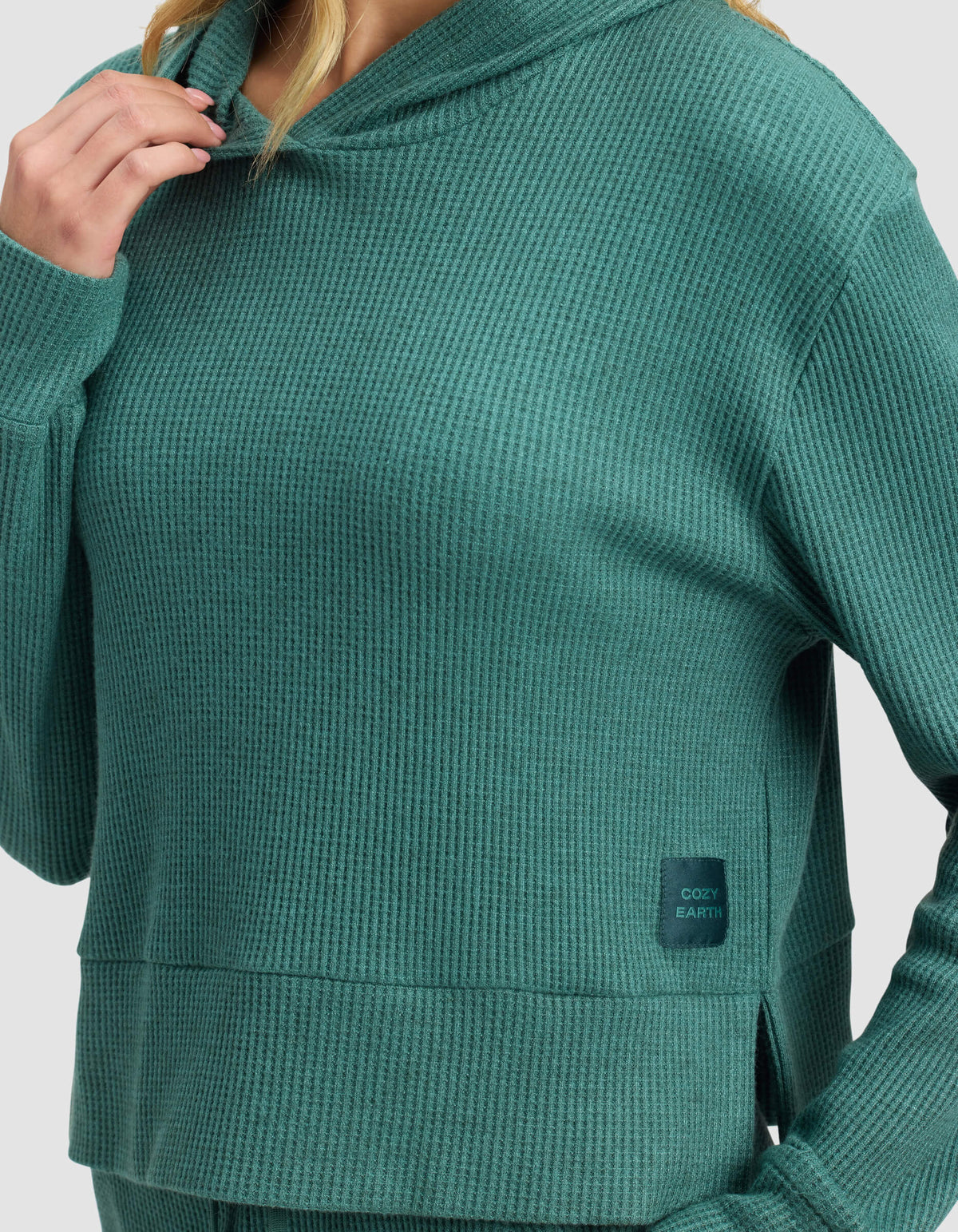 A person wears the Cozy Earth Women's Blake Waffle Hoodie in textured teal-green, featuring a "COZY EARTH" patch on the lower front. The face is partially out of view.|Color:Sea Green