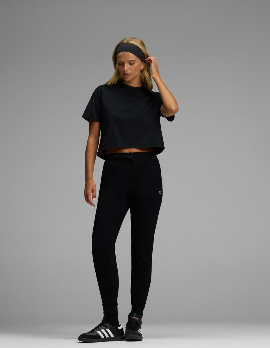 A woman wearing Cozy Earth’s Women’s Brushed Bamboo Jogger stands against a plain gray background.|Color:Black