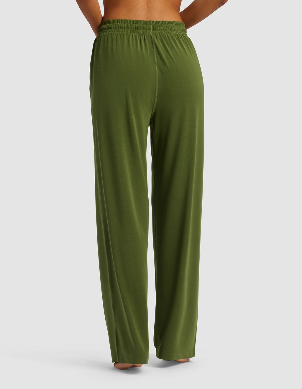 Back view of a person wearing Cozy Earth's Women's Studio Wide Leg Pant in olive green with an elastic waistband, barefoot against a plain light gray background.|Color:Grove