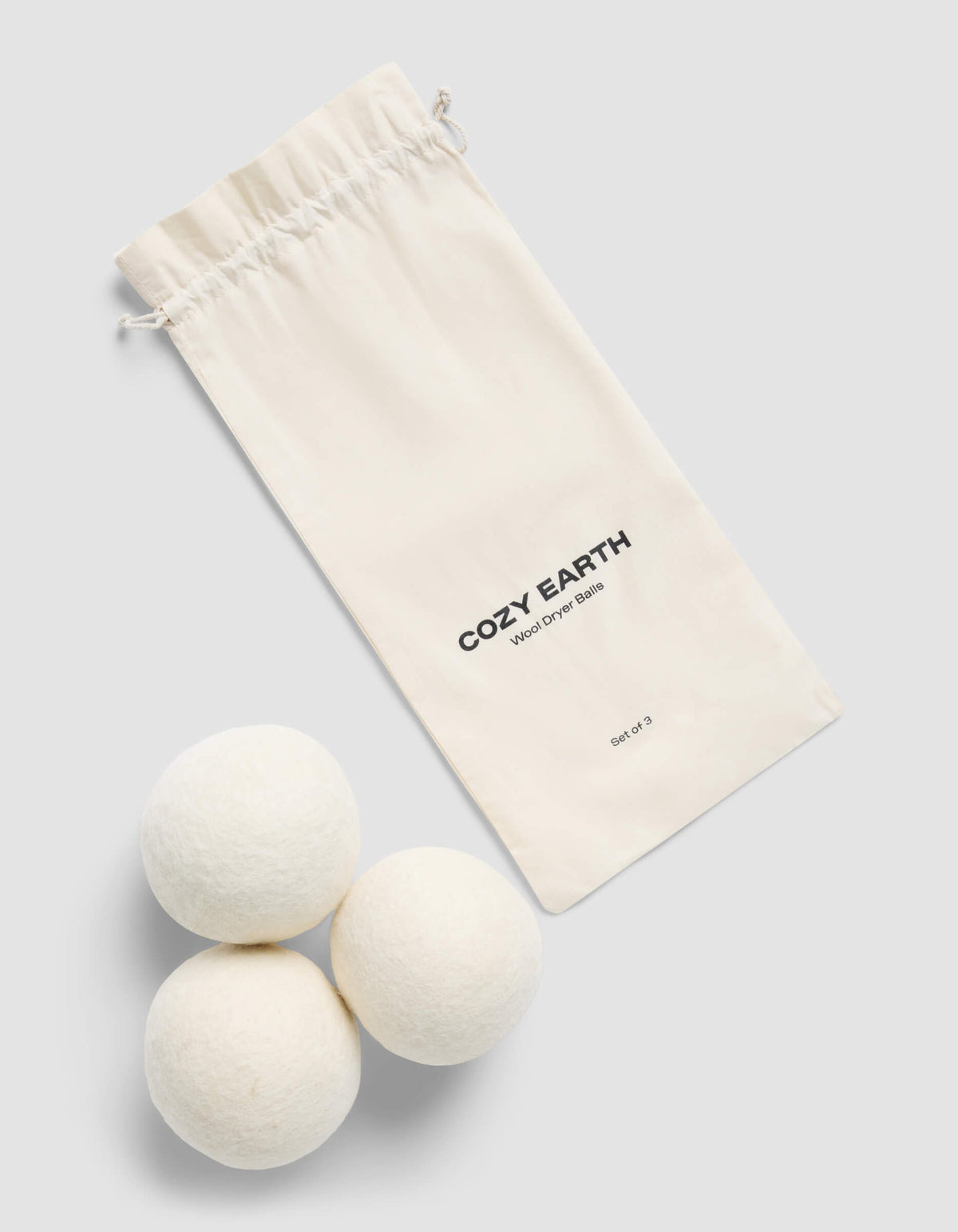 A cream-colored drawstring bag with "Cozy Earth" branding and "Wool Dryer Balls" label sits beside three white wool dryer balls on a light gray background.|Size:Large