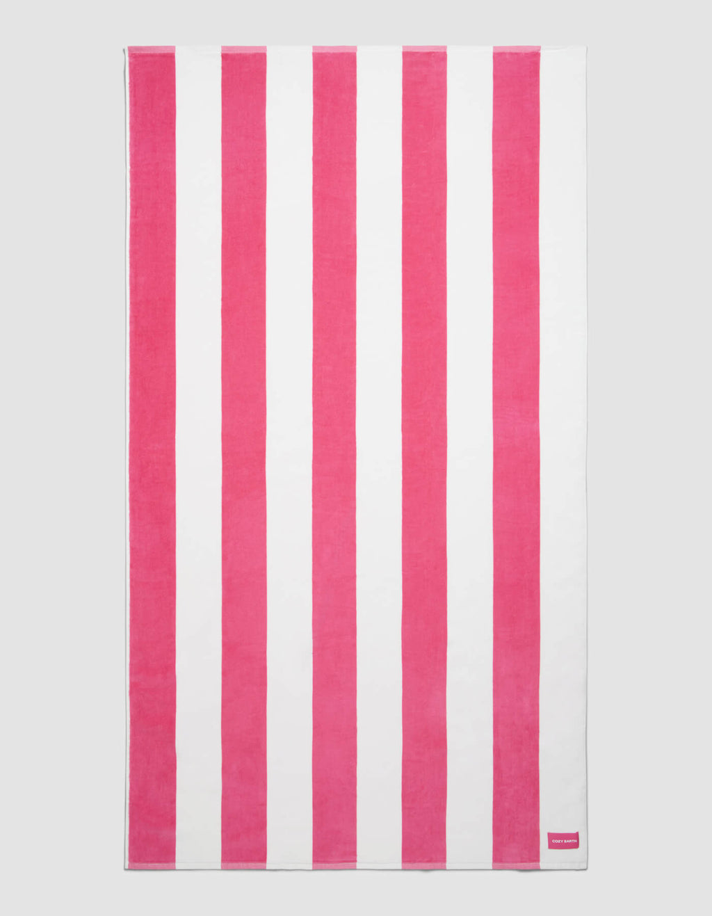 The Cozy Earth Seaside Resort Towel features alternating vertical pink and white stripes on a plain background, with a small pink tag displaying white text in one corner.|Color:Punch Stripe